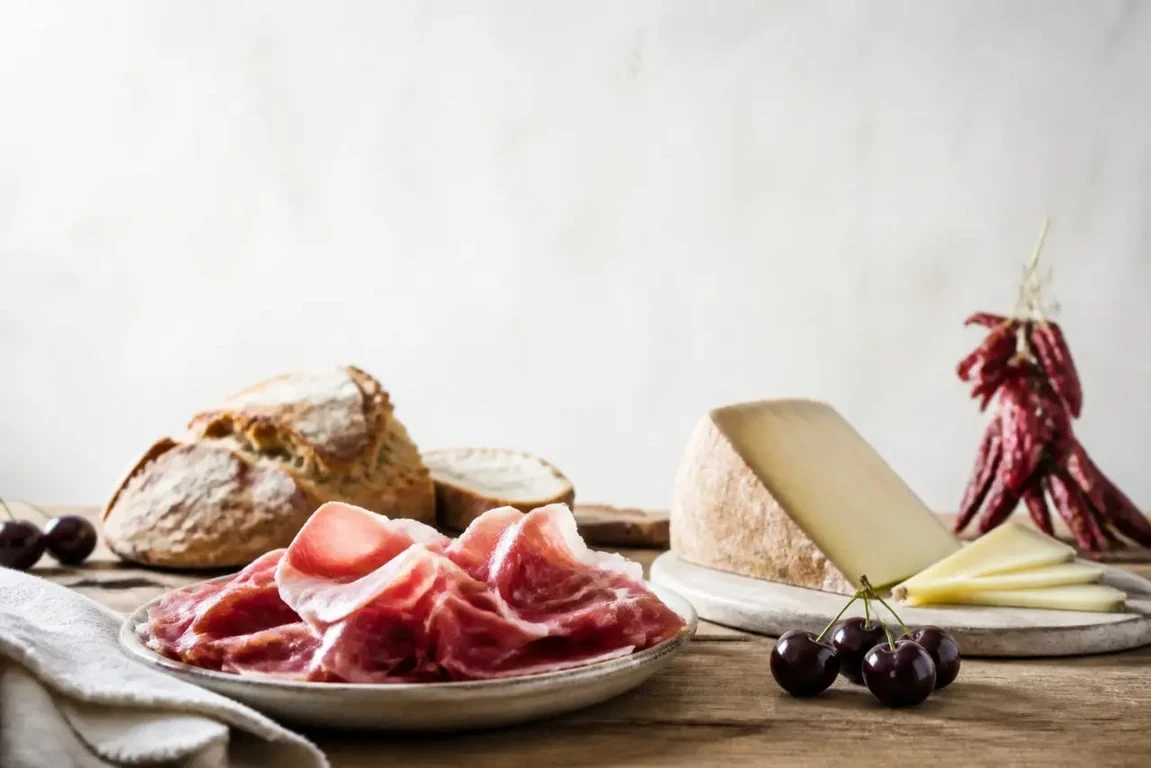 Spécialités basques sur une table rustique avec jambon de Bayonne, piment d’Espelette et Ossau-Iraty